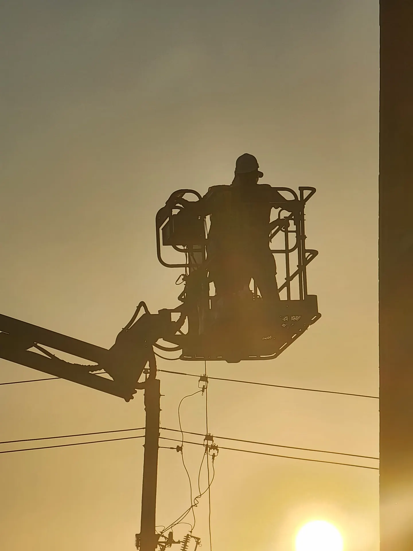 Crew member working from a boom lift at sunrise